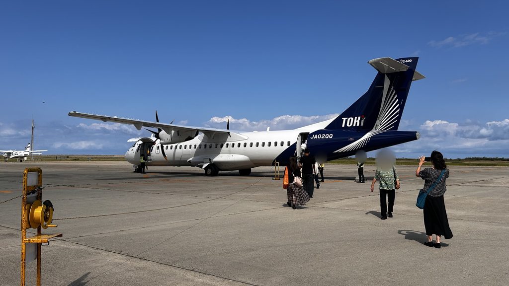 新潟空港の駐機場に止まるトキエアのプロペラ機。紺色の尾翼に白い羽の模様がある