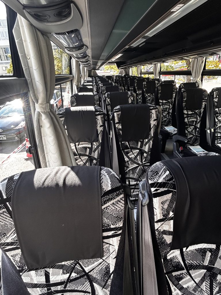 定期観光バスの車内。通路の左右に、模様の入った座席が並ぶ