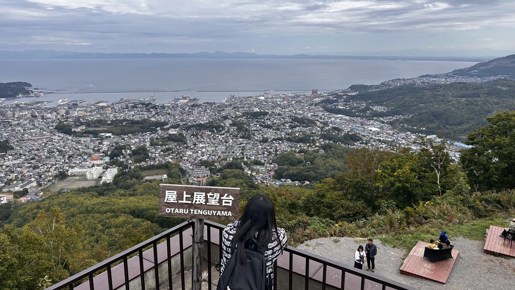 天狗山の屋上展望台から見た小樽の街と海。曇り空の下に市街地が広がっている