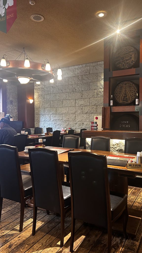 小樽バインの店内。石を積んだ壁とシャンデリア、木のテーブルが並ぶ