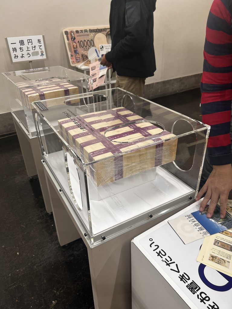 金融資料館の1億円の重さ体験の展示。ガラスケースに模擬紙幣の束が入っている