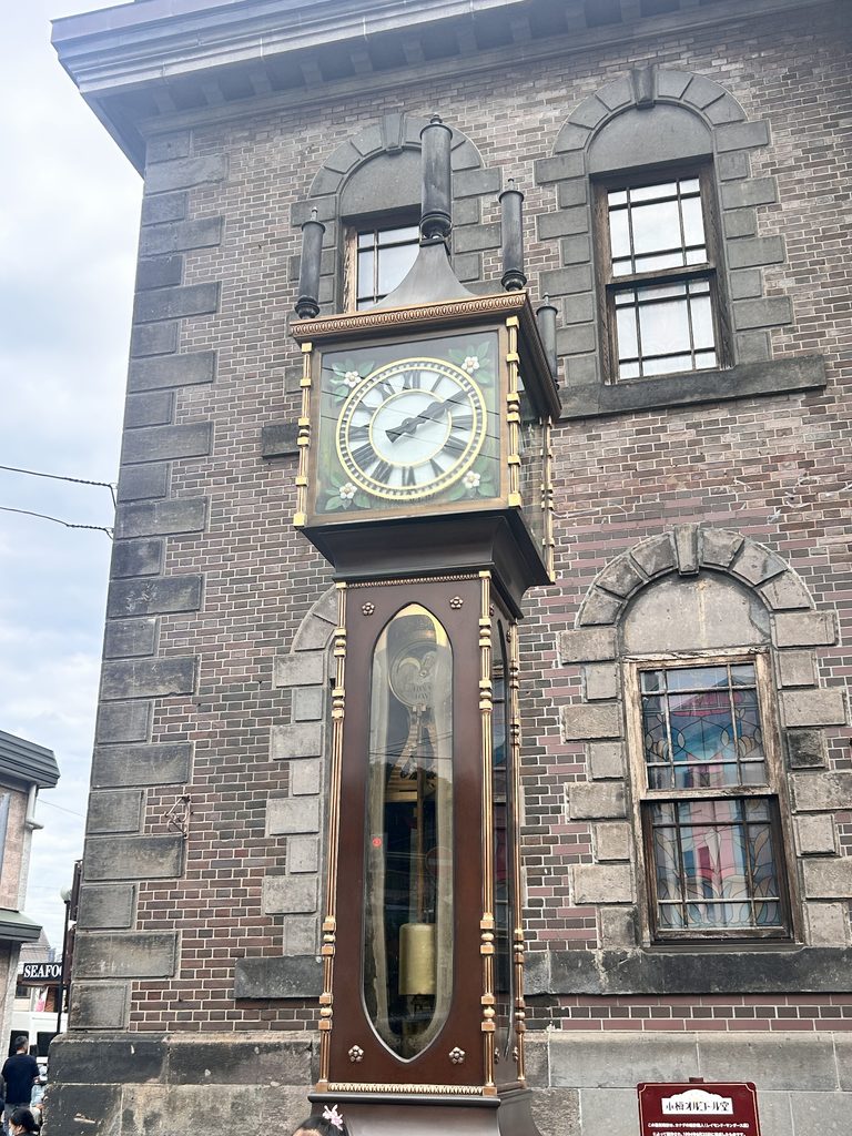 小樽オルゴール堂の前にある蒸気時計。石造りの建物の角に立つ、背の高い時計