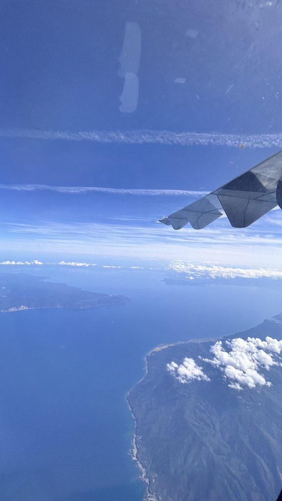 帰りの窓から見た翼と、雲の下の海と陸