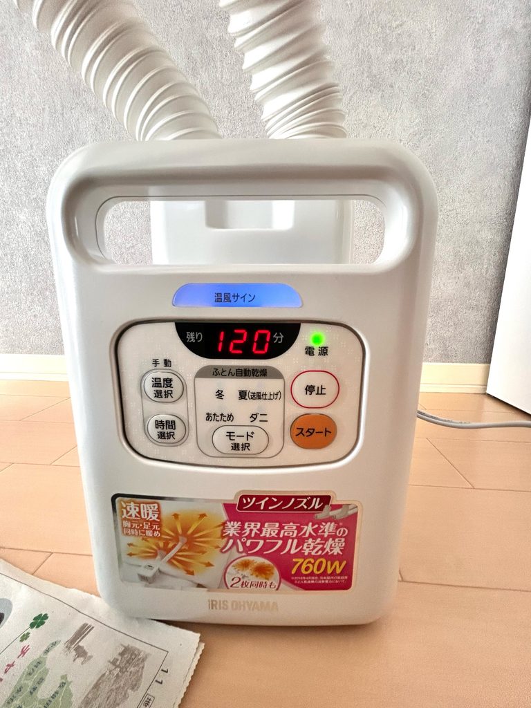 アイリスオーヤマの布団乾燥機の操作パネル。温風サインが青く光り、残り時間は120分と表示されている