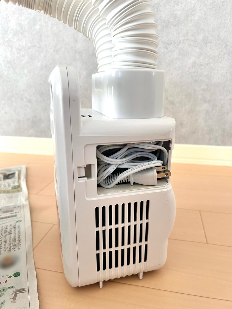 アイリスオーヤマの布団乾燥機のコード収納部のふたを開けたところ。電源コードが束ねて入っている